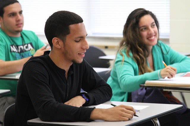 Three students are sitting on their desk chair.